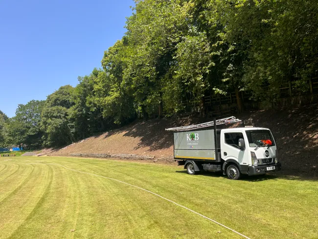 Grounds maintenance truck beside a cleared and mown bank
